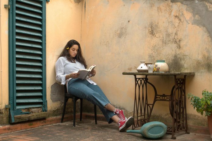 woman in white long sleeve shirt and blue denim jeans sitting on black wooden chair best ap comparative government review book